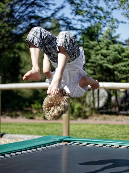 man in white t-shirt and blue and white plaid shorts sitting on blue metal bench