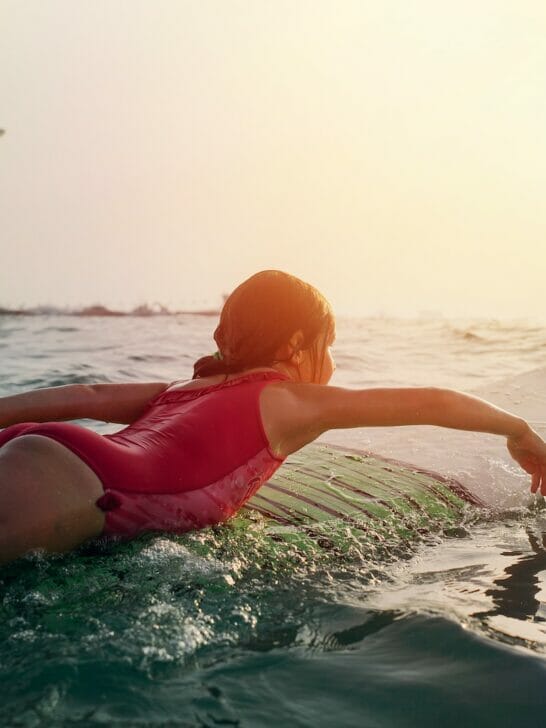 girl on top of white surfboard beside Burj Al Arab