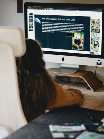 woman in black shirt sitting in front of silver imac