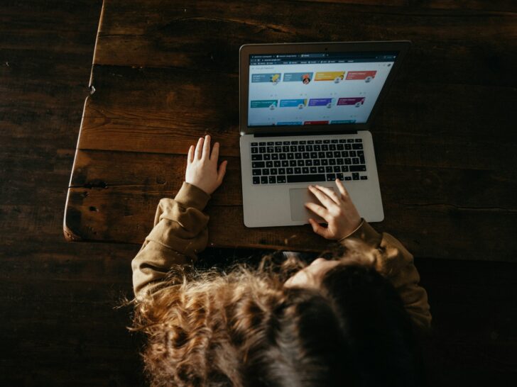 person using macbook pro on brown wooden floor