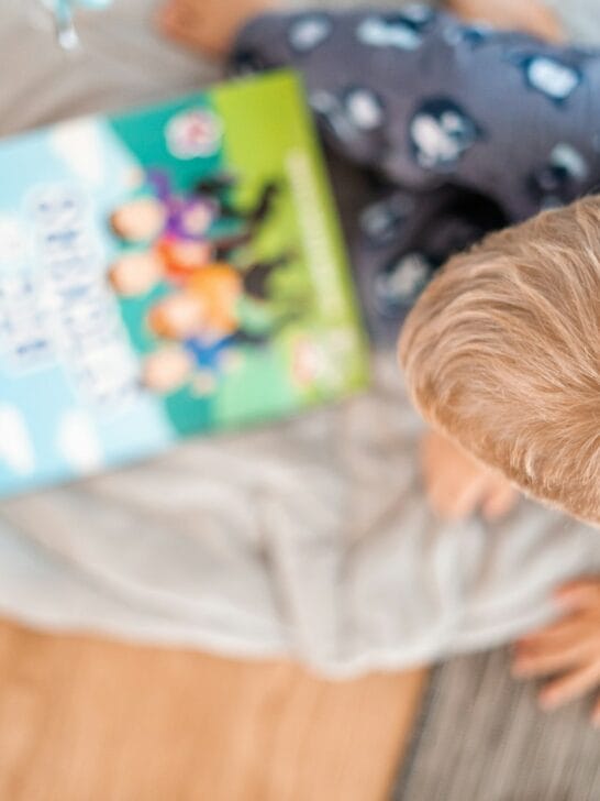 a little boy reading a book on a bed