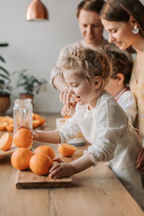 Joyful family with children making fresh orange juice in a bright kitchen setting.