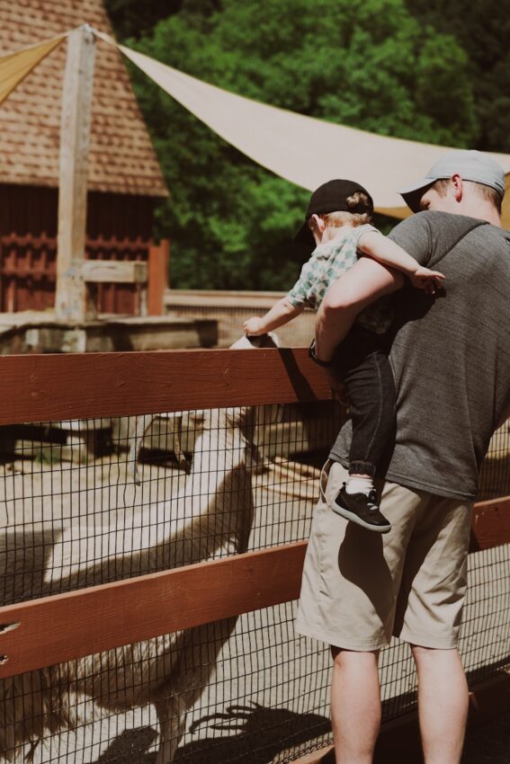 A man holding a child in his arms at a zoo