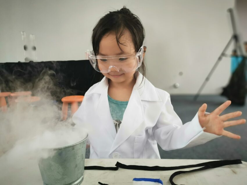 a little girl wearing a white lab coat and goggles