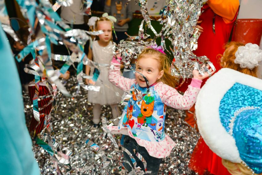 Joyful children having fun at an indoor party, with colorful streamers adding to the festive atmosphere.