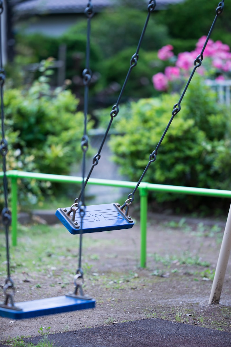 black metal swing on green grass field during daytime