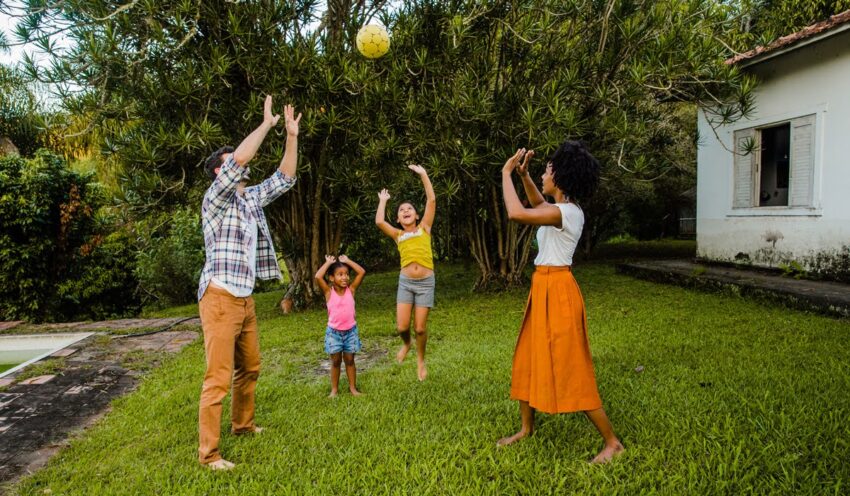 Family playing with a yellow ball in their backyard