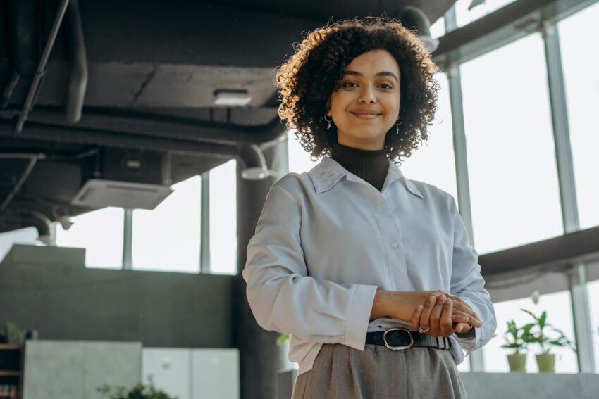 A confident businesswoman smiling in a modern office environment, exuding professionalism and warmth.