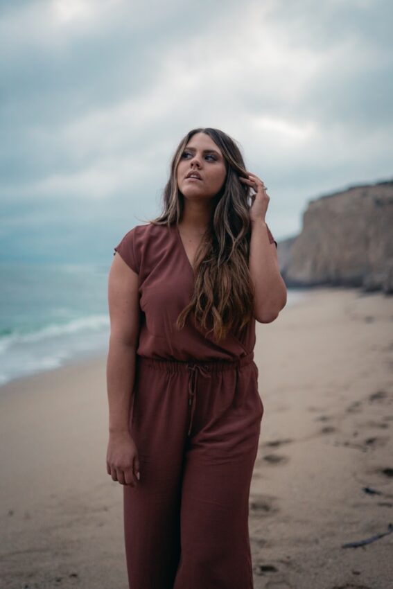 woman in red dress standing on beach during daytime