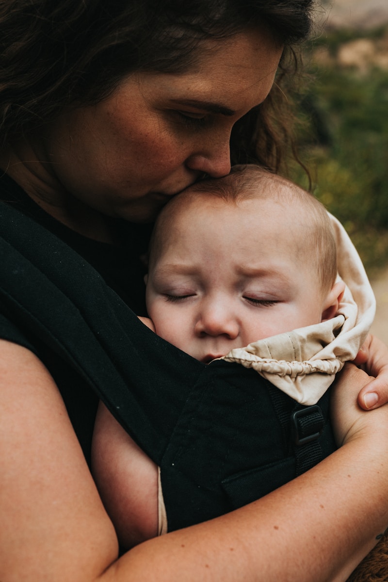 woman in black sleeveless shirt carrying baby in white onesie