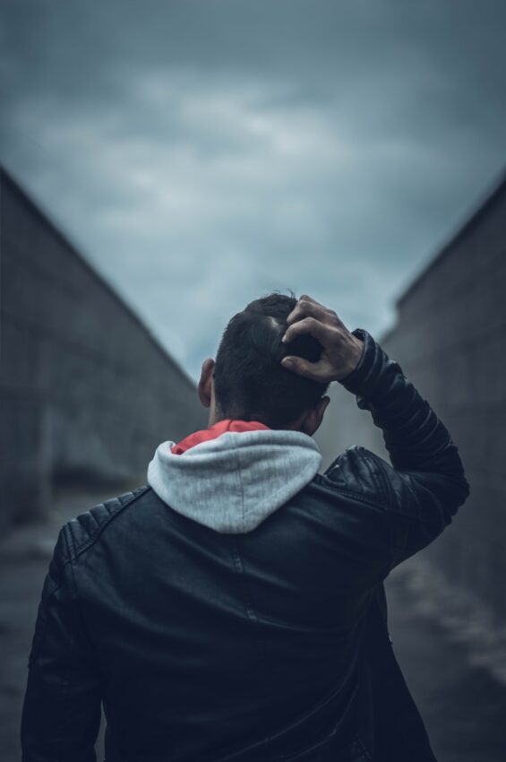 man in black leather jacket covering his face with white and red scarf
