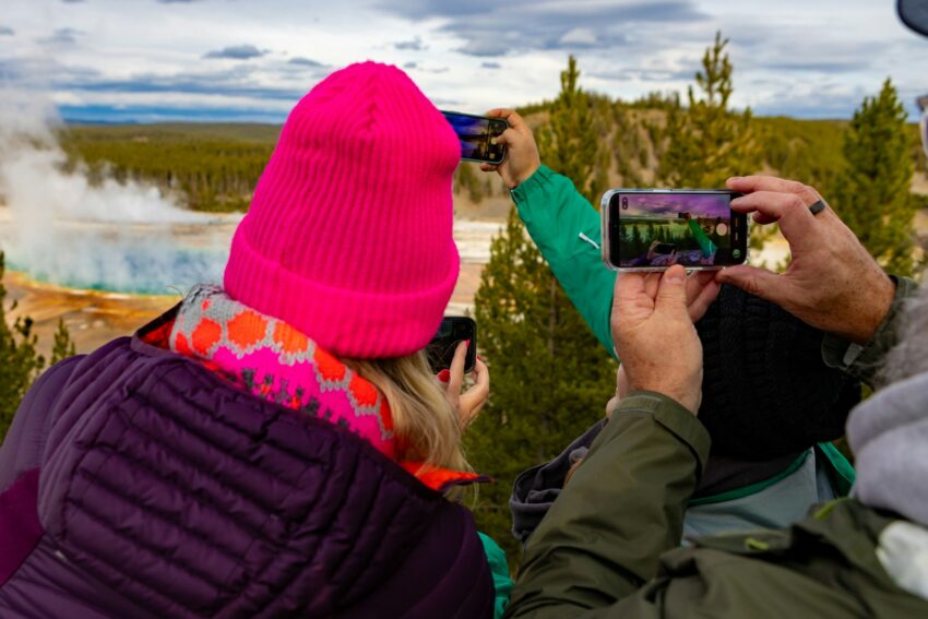 Tourists photograph a colorful hot spring landscape.